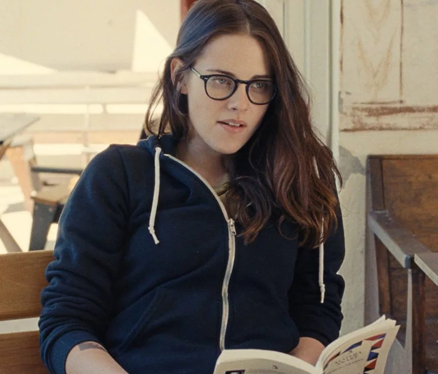 Киноактриса Кристен Стюарт в очках с учебником.