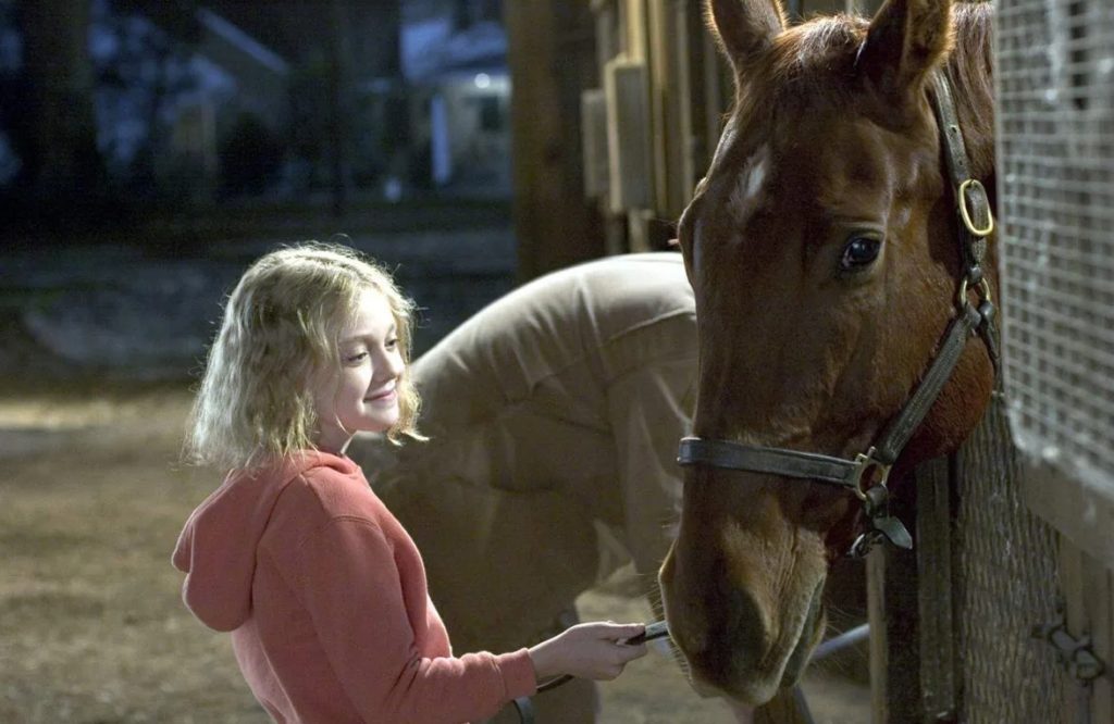 Актриса Дакота Фаннинг в детстве кормит лошадку.